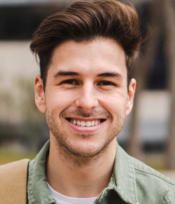 Young man smiling at camera wearing green shirt, professional headshot style portrait.