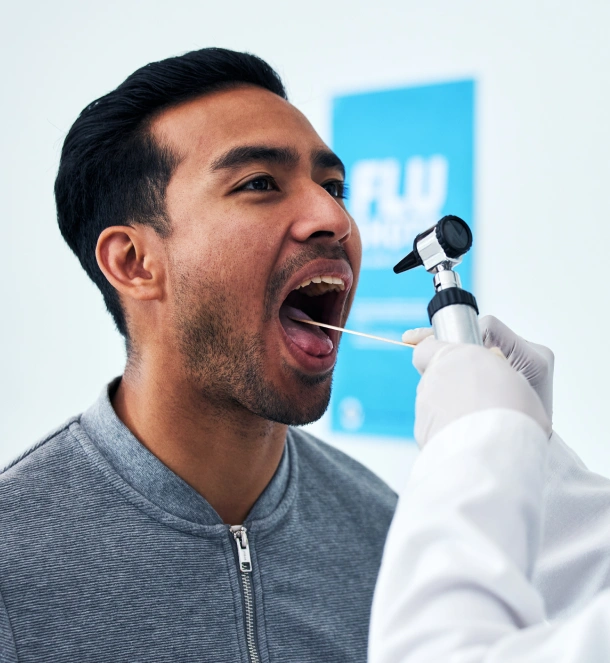 Man receiving dental examination from dentist in clinical setting with blue background.