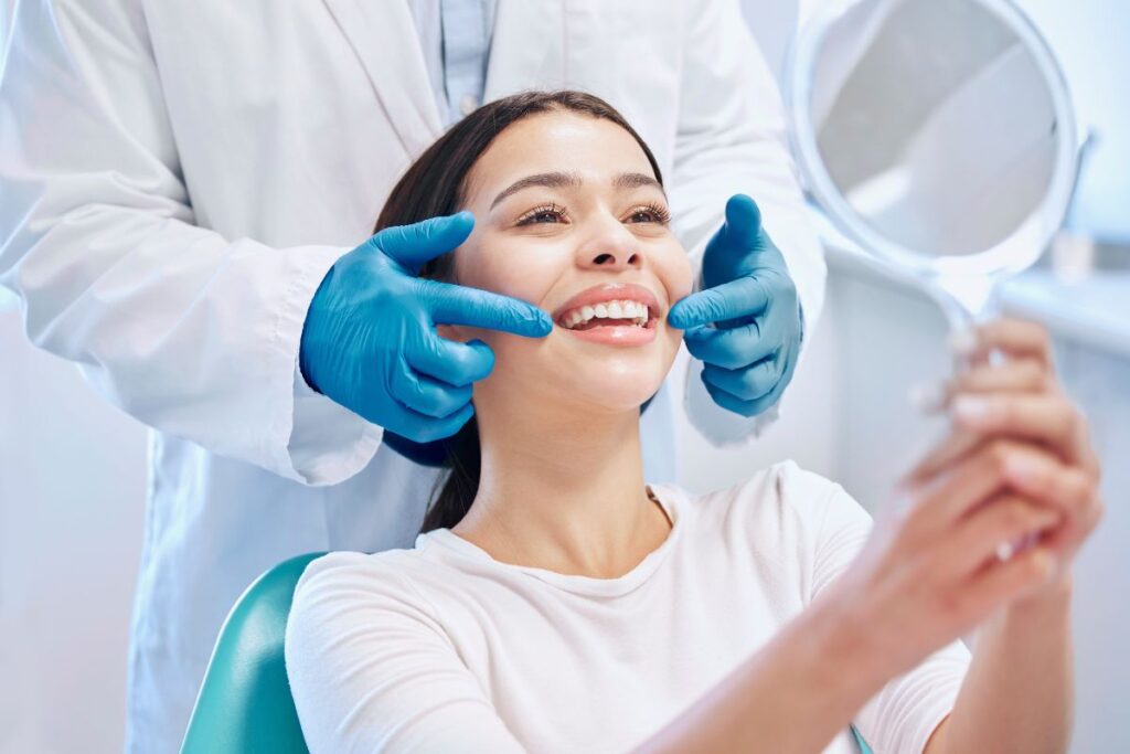 A dentist helps a patient evaluate her smile in a mirror, highlighting a natural-looking cosmetic dental treatment result.
