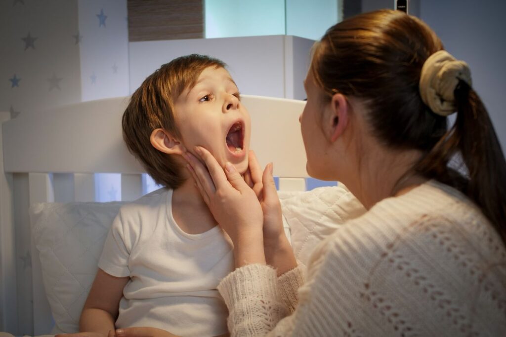 A parent gently checks a child’s mouth at home, showing how parents can monitor their child’s dental development during the tooth-losing stage.