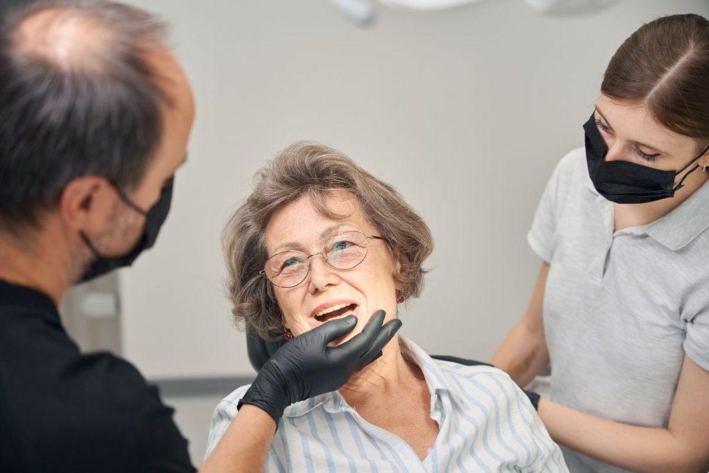 Dentist evaluating an older patient's oral health and discussing denture care during a dental appointment.