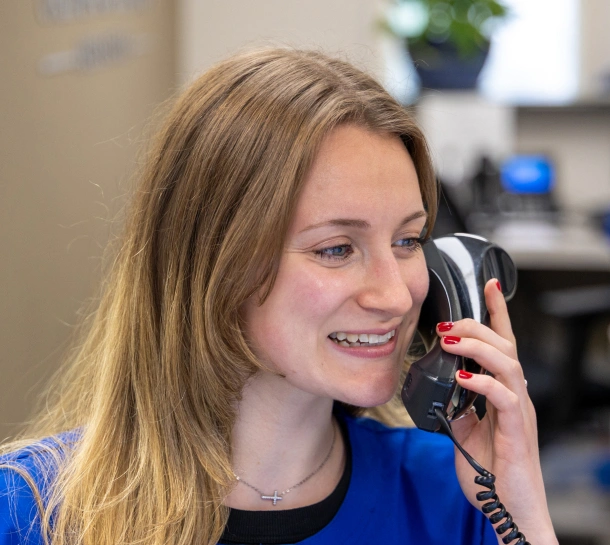 Front desk staff member smiling on the phone with a patient