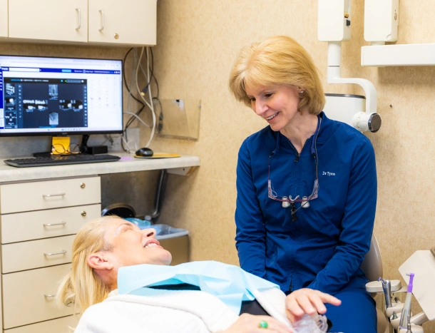 Dentist smiling and talking with a patient in the dental chair