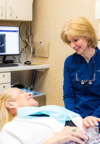 Dentist smiling and talking with a patient reclined in the dental chair
