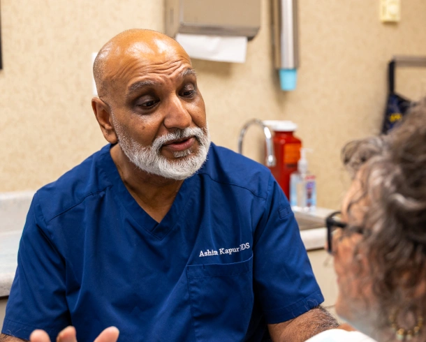Dentist in scrubs speaking with a patient during a consultation