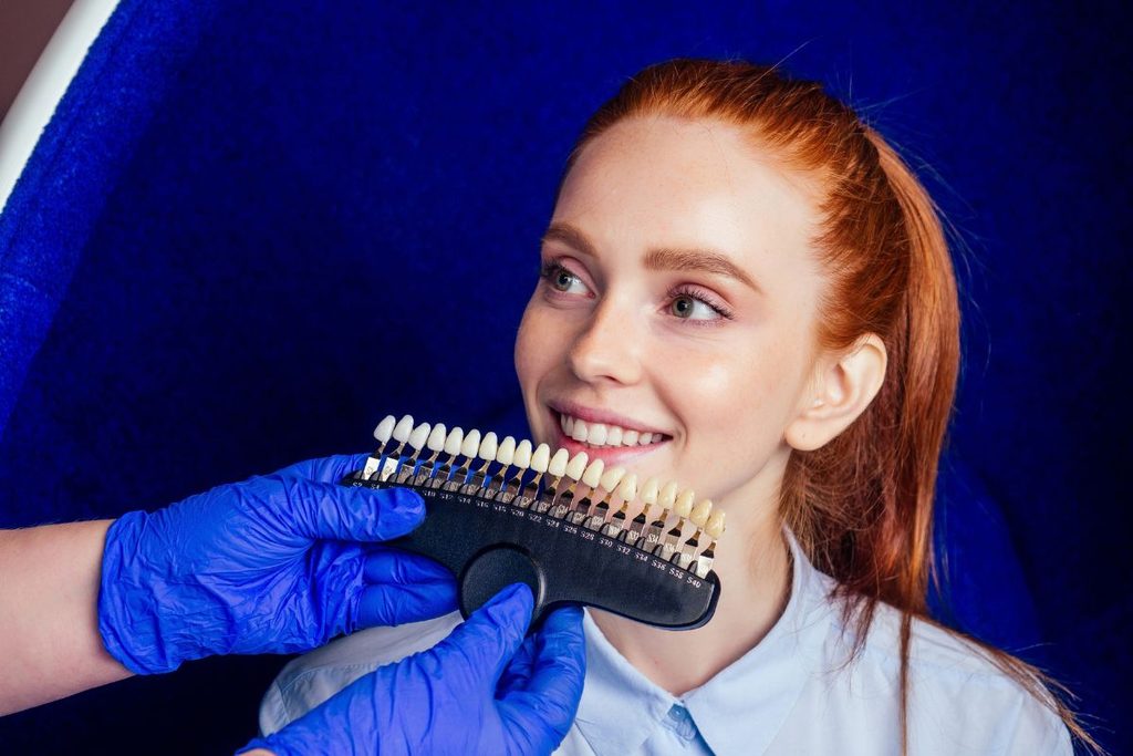 Dentist comparing veneer shades with a patient during a cosmetic dental consultation for dental veneers.